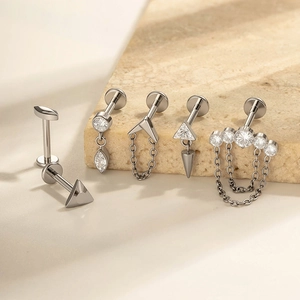 Titanium piercing set with zircons and chains shown on stone blocks