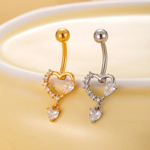 Macro detail of gold and silver heart-shaped navel rings with sparkling cubic zirconia inlay
