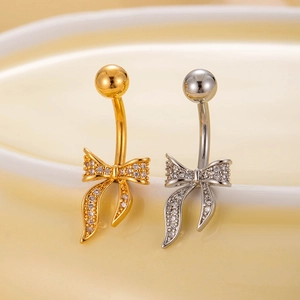 Detail shot of gold and silver bow belly rings with cubic zirconia inlay on ceramic