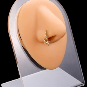 Piercing de nariz mariposa dorada con circones en un modelo de nariz de silicona realista