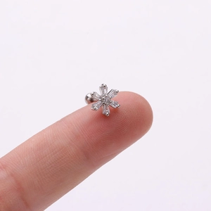 Gros plan d'un clou d'oreille flocon de neige avec zircone sur un doigt