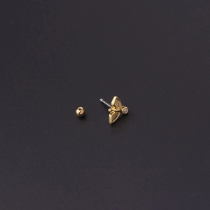 Detailed close-up of a gold winged ear stud with a zircon inlay and screw ball back