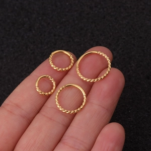 Detailansicht von vier goldenen gedrehten Clicker-Ringen an Fingern in verschiedenen Größen