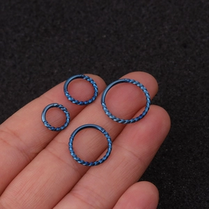 Detail von blauen gedrehten Edelstahl-Creolen in vier Größen in der Hand gehalten