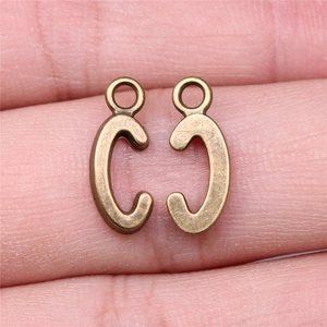 Set of two vintage bronze letter C pendants for DIY jewelry making on a finger for scale