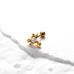 Macro d'un piercing hélix en acier doré avec opale, zircon et pendentif en forme de cœur