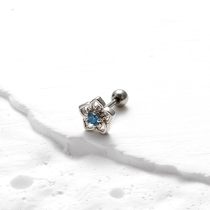 Détail du piercing fleur argenté avec zircon bleu et fermoir à boule vissée