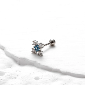 Gros plan d'un piercing hélix avec fleur en croix et pierres de zircone bleues
