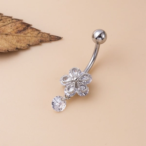 Detail of silver navel piercing with zircon flower pendant and curved barbell on beige background