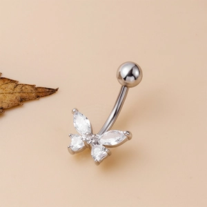 Close-up of a silver butterfly belly button ring with zircon stones on a beige backdrop