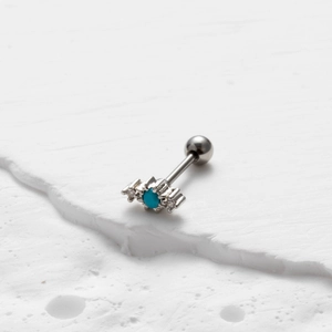 Macro-opname van barbell-oorknopje met turquoise steen in gepolijst roestvrij staal