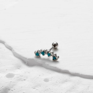 Macro detail van een blauwe turquoise gebogen kraakbeen piercing van staal