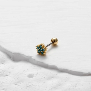 Macrodetail van de turquoise stenen cluster oorpiercing met gouden klauwzetting en schroefdop