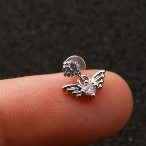 Detailed close-up of a silver labret stud with angel wing pendant and zircons on a finger