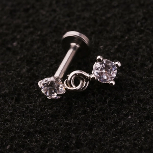Macro detail of silver stainless steel labret stud with double hanging clear cubic zirconia