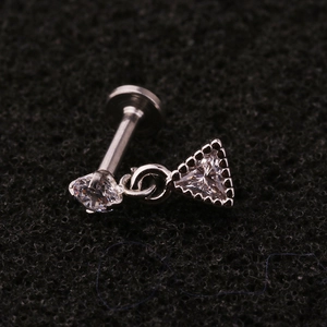 Macro shot of stainless steel labret stud with triangular zircon pendant on black foam