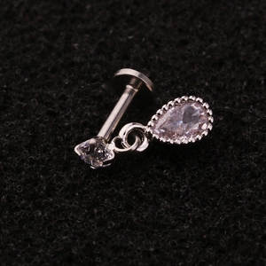 Macro shot of stainless steel labret stud with dangling water drop zircon and vintage texture