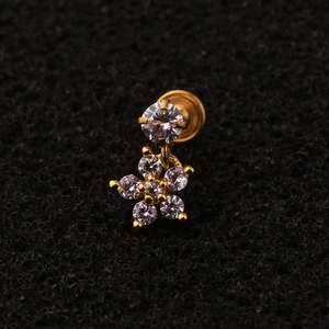 Macro shot of gold floral tragus piercing with sparkling zircon stones on black foam
