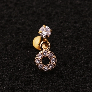 Macro shot of gold labret piercing with clear zircon stone and round paved dangle charm