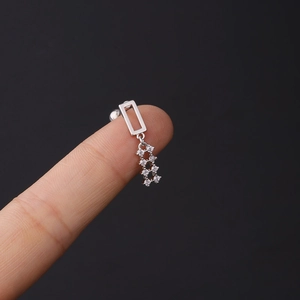 Detailed macro view of silver steel earrings with zircon fringes held on a fingertip