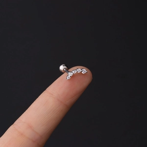 Macro shot of curved 16G stainless steel labret stud with five clear zircon stones on finger
