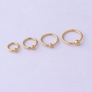 Macro shot of four golden stainless steel seamless nose rings with fixed bead detail