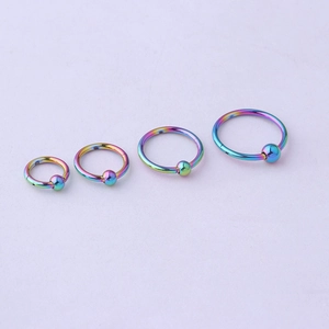 Close-up of four rainbow-plated stainless steel seamless captive bead rings in various sizes