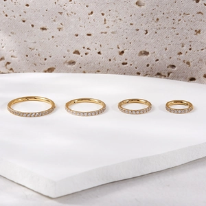 Detail view of four gold titanium hinged rings with zircon stones in different sizes