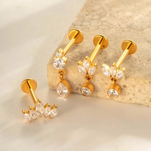 Set aus vier goldenen G23 Titan Piercings mit Zirkoniasteinen auf Dekostein