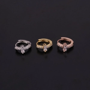 Detail of silver, gold, and rose gold hoop earrings with baguette-cut zircon stones