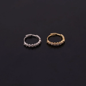 Macro view of gold and silver hoop earrings with cubic zirconia inlay on grey background