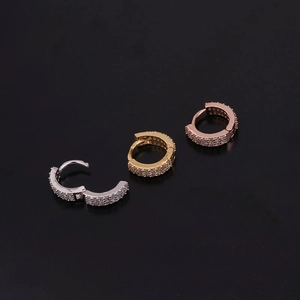 Macro shot of silver, gold, and rose gold huggie earrings with cubic zirconia stones