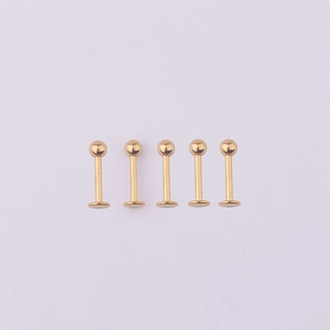 Five gold 316L stainless steel labret studs with ball tops aligned on purple background