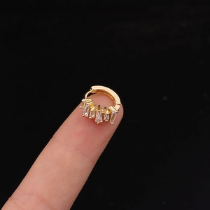 Κοντινή λήψη χρυσού ear cuff με πέντε διάφανες ζιρκόνιες σε σχήμα βεντάλιας και κοπή σκάλας