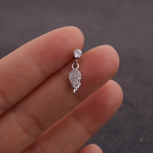 Détail d'un piercing d'oreille en acier argenté avec zircone et pendentif plume ciselé