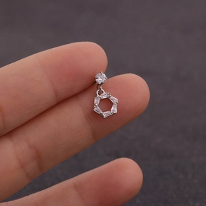 Gros plan du piercing en acier argenté avec zircon baguette dans un cadre hexagonal