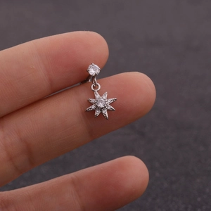 Détail d'un piercing en acier argenté avec pendentif étoile boussole serti de zircons