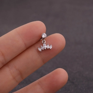 Détail macro d'un piercing d'oreille en acier inoxydable avec zircons tenu à la main