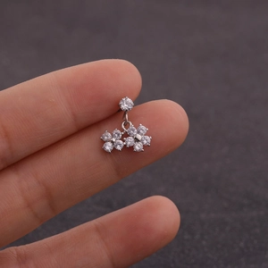 Détail d'un piercing d'oreille en forme de fleur argentée serti de zircons brillants