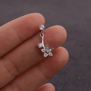 Vue macro d'un piercing nombril argenté avec fleur en zircon et détails pendants