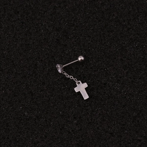 Détail macro d'une boucle d'oreille en acier avec pendentif croix et cristal zircon