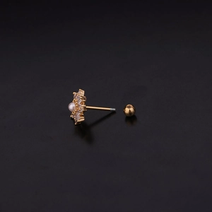 Détail macro du clou d'oreille fleur dorée avec pétales en cristal et centre en perle