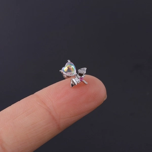 Detailed macro view of heart-shaped opal earring with wing design on a finger