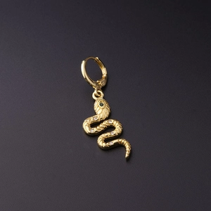 Detail of gold snake earring with textured scales, white crystals and green stone eye