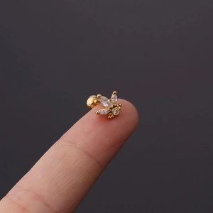 Macro shot of gold bee stud earring with clear zircon crystals on a finger tip