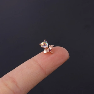 Macro shot of a rose gold heart stud earring with moonstone inlay held by fingers