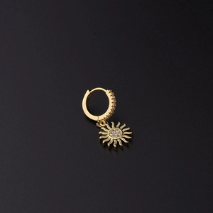 Detalle de pendiente de sol dorado con micro-pavé de circonitas sobre fondo negro