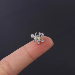 Macro view of tiny opal planet cartilage stud earring held on a fingertip