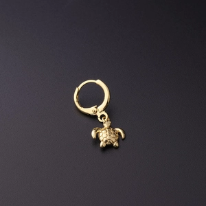 Close-up of golden turtle drop huggie earring featuring detailed shell texture engraving