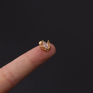 Detailed macro view of a 16G gold crown tragus stud with marquise zircon held between fingers